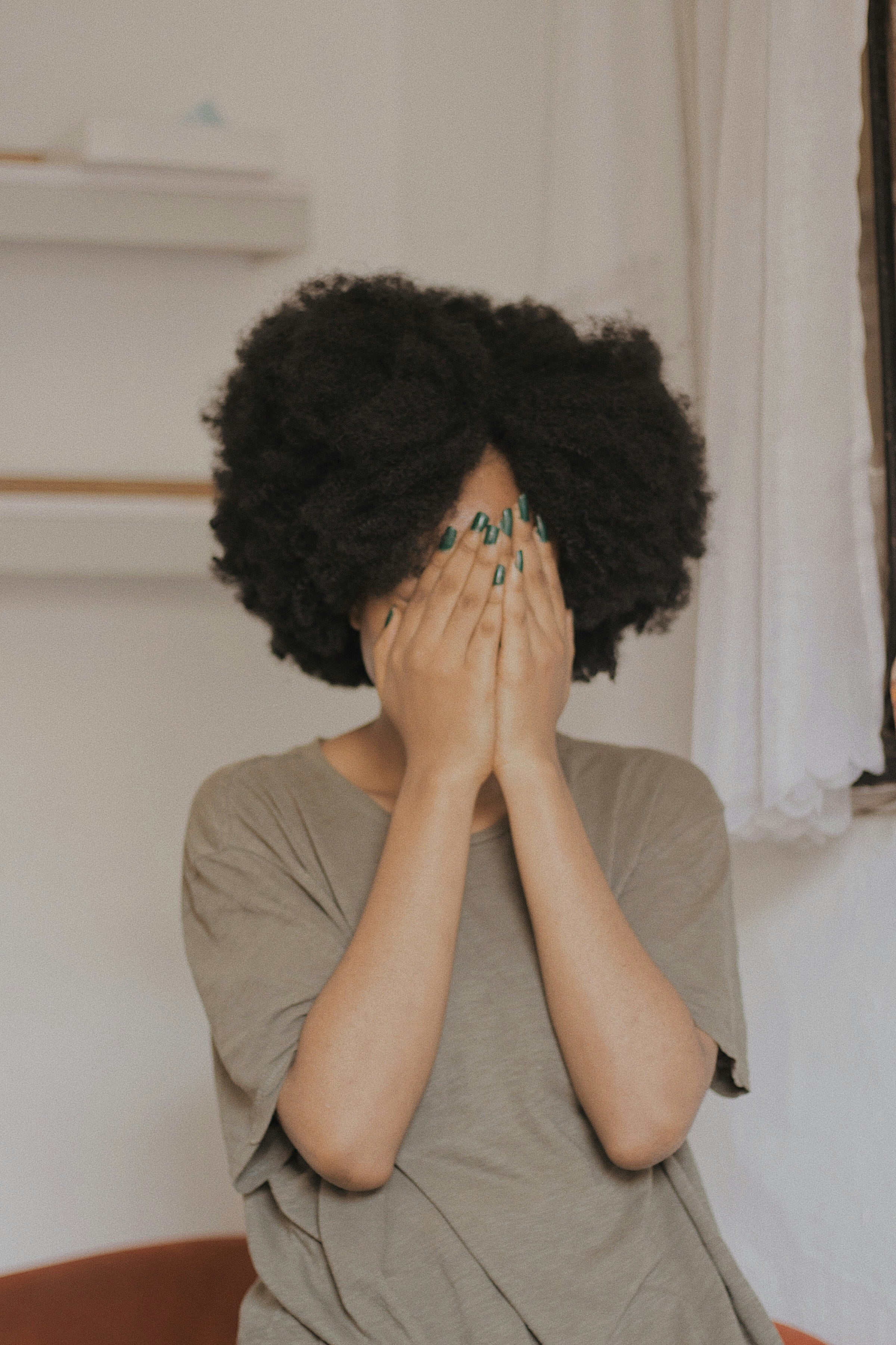 Femme aux cheveux afro volumineux couvrant le visage, soin capillaire texturé